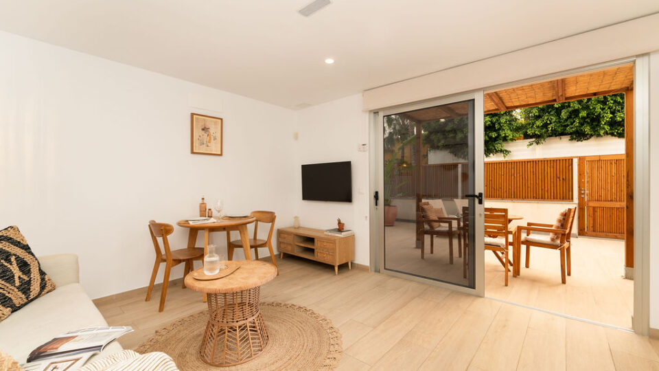 Interior de los apartamentos Mångata Gran Canaria con vista del salón interior con sofá, mesa, Smart TV y puerto de acceso a la terraza