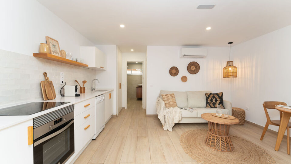 Interior de los apartamentos Mångata Gran Canaria con vista del salón interior con sofá, mesa y la cocina
