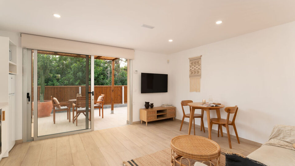 Interior de los apartamentos Mångata Gran Canaria con vista del salón interior con sofá, mesa, Smart TV y puerto de acceso a la terraza