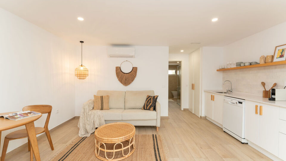 Interior de los apartamentos Mångata Gran Canaria con vista del salón interior con sofá, mesa y la cocina