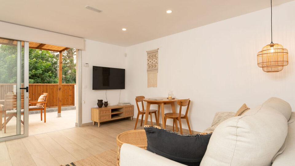 Interior de los apartamentos Mångata Gran Canaria con vista del salón interior con sofá, mesa y Smart TV